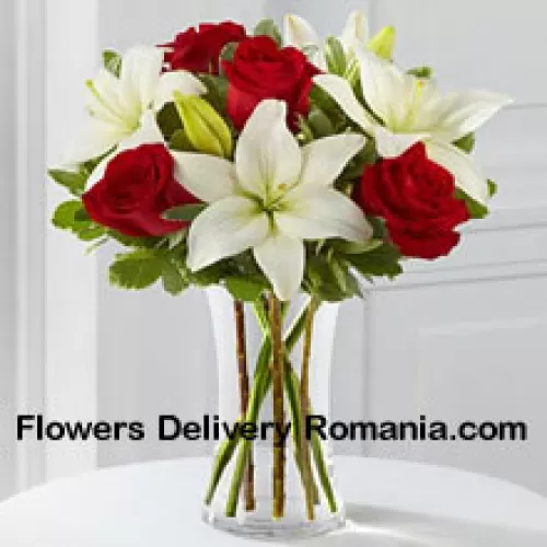 Rote Rosen und weiße Lilien mit einigen saisonalen Füllern in einer Glasvase